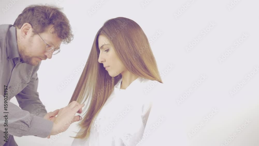 Hairstylist cutting long layers hair of beautiful model slow motion retro style Hairstylist cutting long layers hair of beautiful model slow motion retro style
