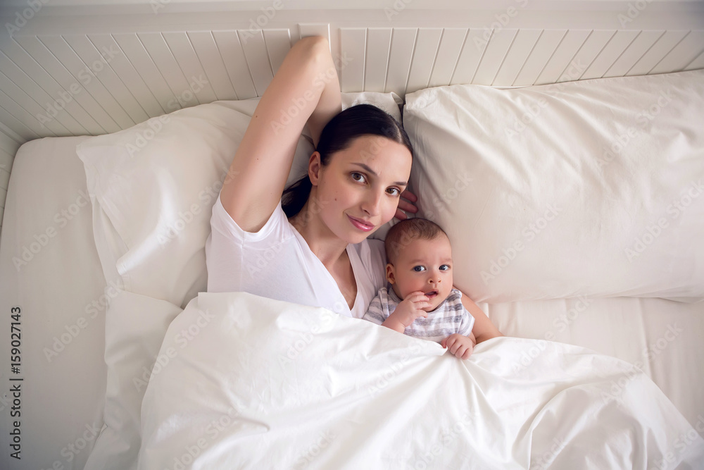 mom with a newborn son lying on a white bed mom with a newborn son lying on a white bed