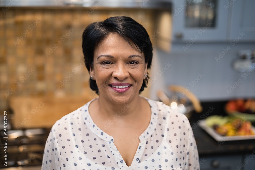 Portrait of smiling mature woman standing in kitchen Portrait of smiling mature woman standing in kitchen