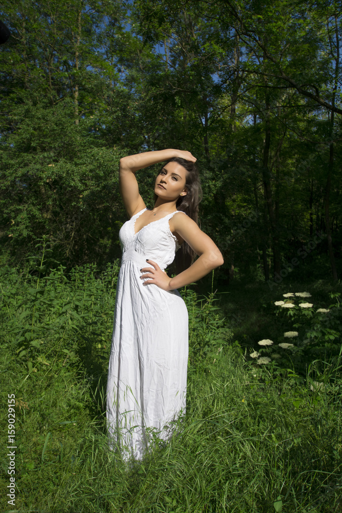 Young girl with white dress posing in a grass field Young girl with white dress posing in a grass field