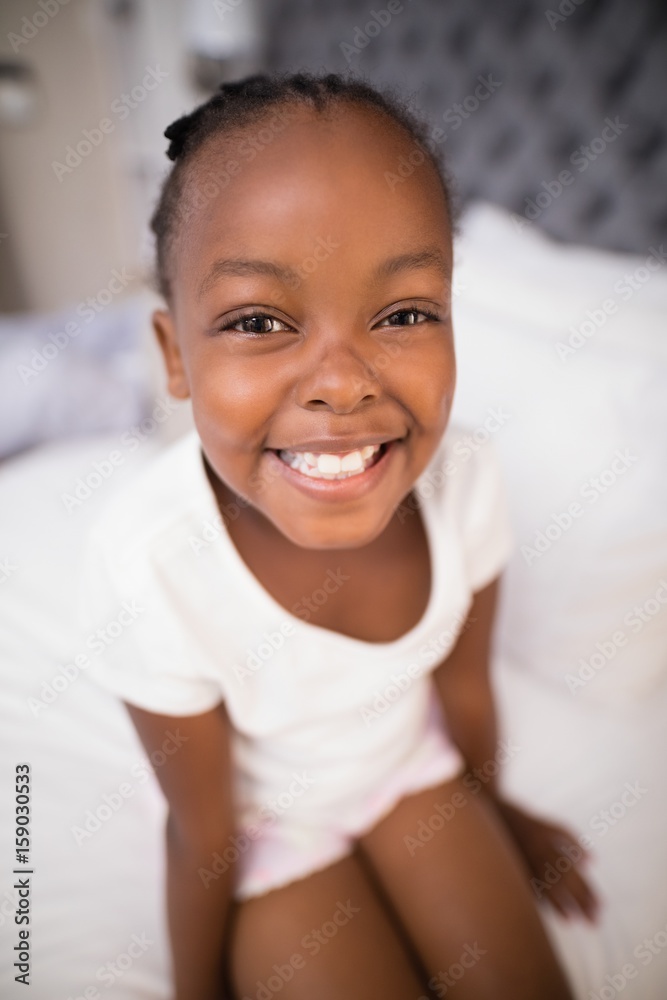 Portrait of smiling girl sitting on bed
