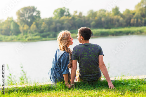 couple in love sitting near the summer lake shore