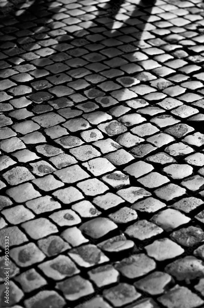 Faint shadow of a man on cobblestone street
