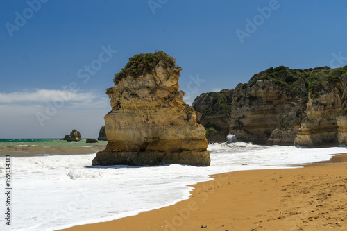 Very beautiful portugese beach with rocks, aquamarine sea and dark yellow sand