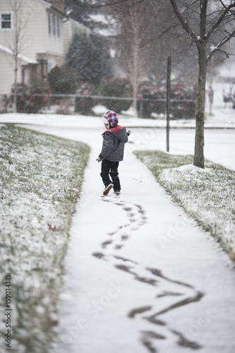 Boy making zig zag tracks in first snow of the season 