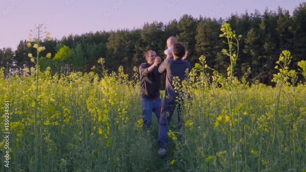 mother, father and son dancing and playing in the rapeseed field Slow motion mother, father and son dancing and playing in the rapeseed field Slow motion