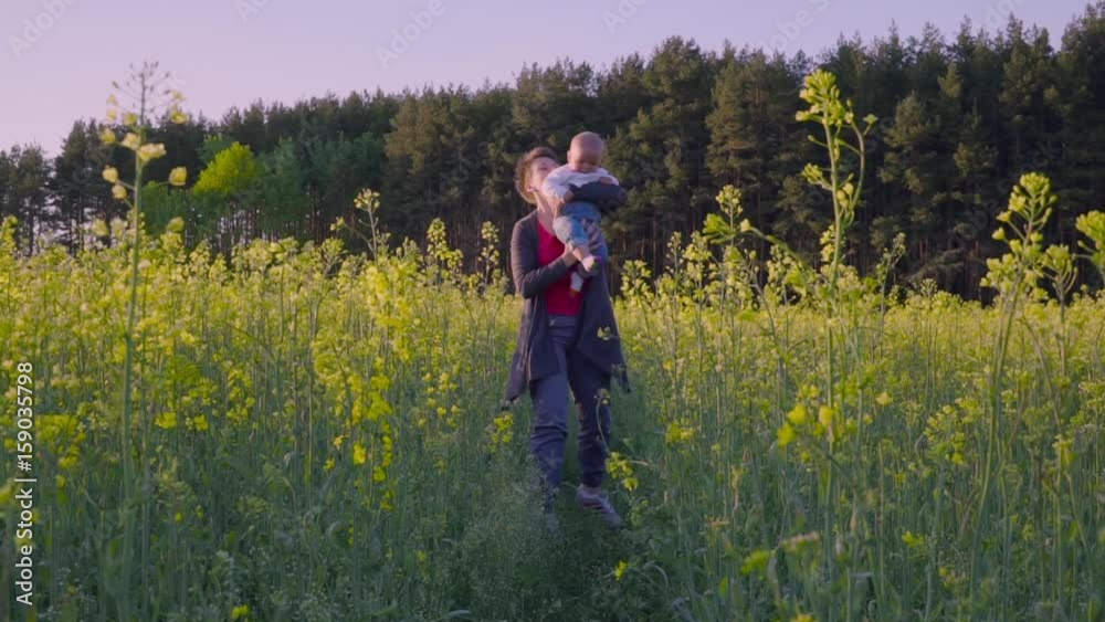 mother, father and son dancing and playing in the rapeseed field Slow motion mother, father and son dancing and playing in the rapeseed field Slow motion