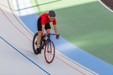 Racing cyclist on velodrome outdoor. Professional athlete in a red T-shirt and a black bicycle.