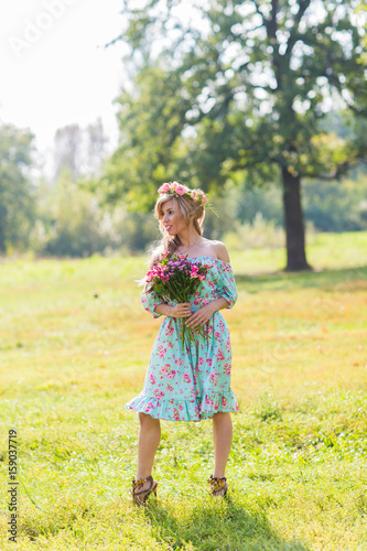 Beautiful blonde girl holding bouquet of flowers at the countryside