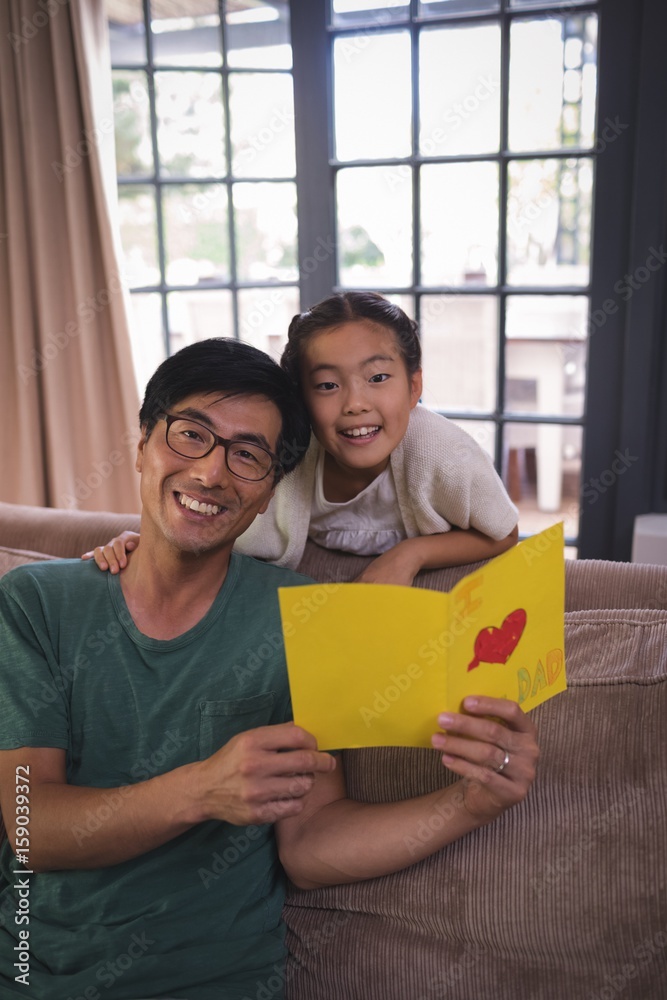 Obraz premium Father and daughter holding greeting card in living room