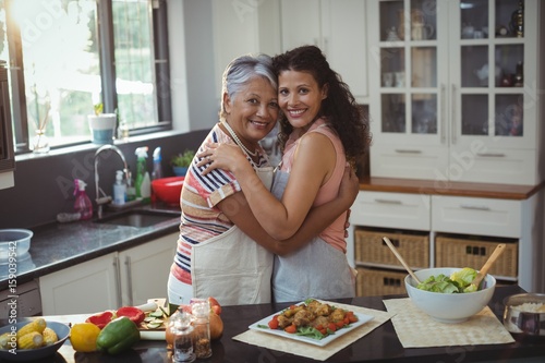 Mother hugging daughter in kitchen