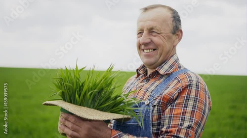 Elderly male farmer with green plants in his hat photo