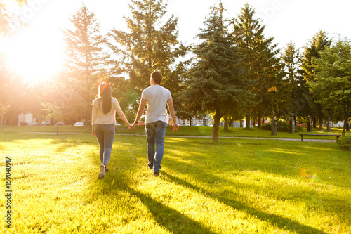 Lovely couple at park walking together on sunny day holding their hands