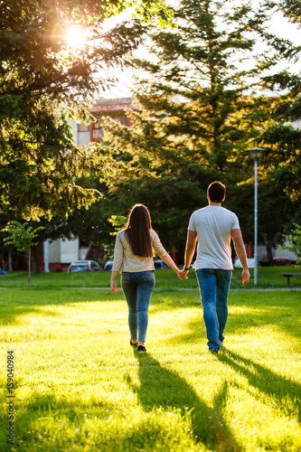 Lovely couple at park walking together on sunny day holding their hands
