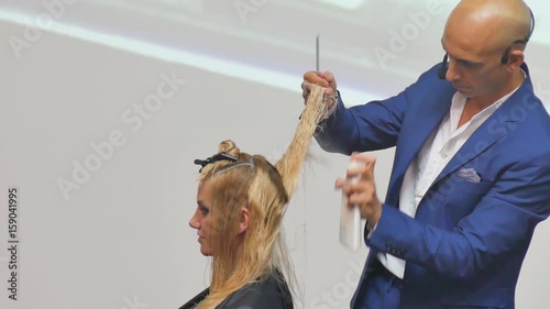 Stylist man cuts hair blonde Italian in a hairdressing salon photo