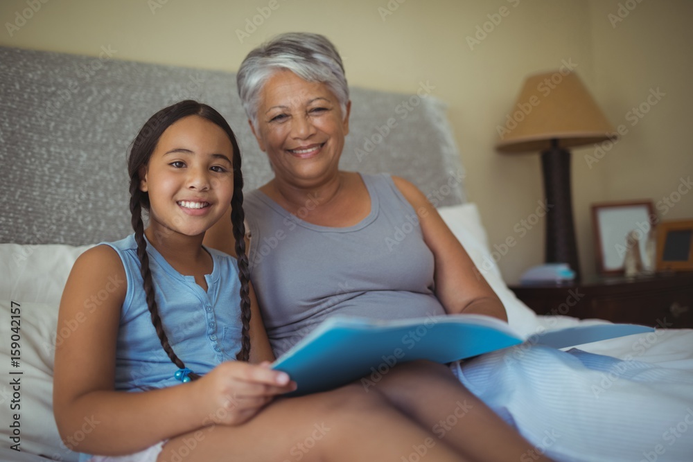 Grandmother and granddaughter holding photo album in bed room Grandmother and granddaughter holding photo album in bed room