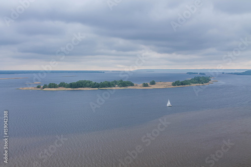 A white sailboat in the middle of the river. A lonely sailboat.