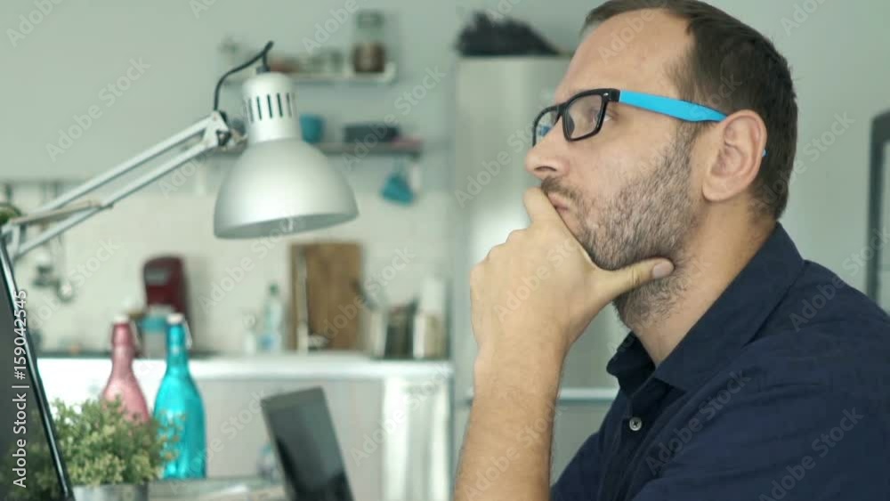 Young man with pc computer thinking, truing to solve problem at home