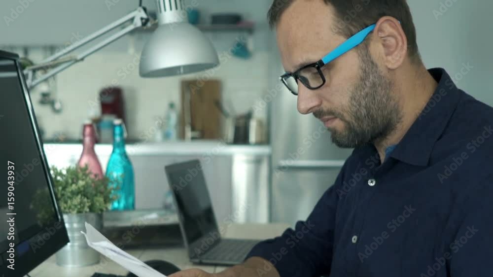 Young man working with documents sitting by table at home
Young man working with documents sitting by table at home