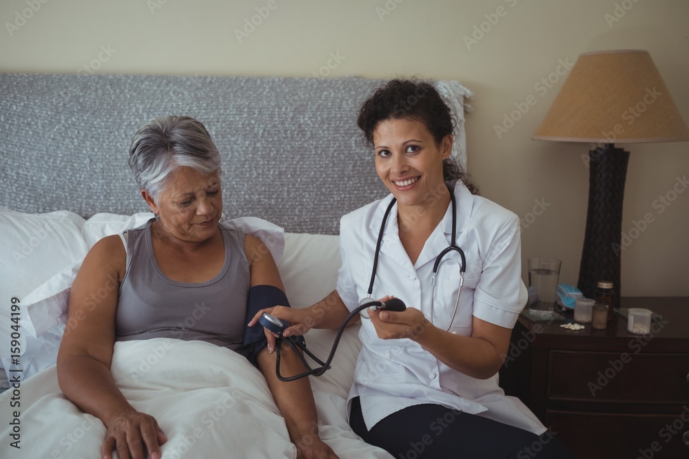 Obraz premium Female doctor measuring blood pressure of a senior woman