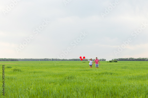 beautiful young couple hugging and kissing in a field with colored balloons