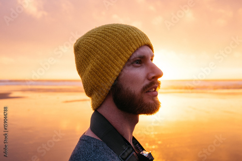 side profile portrait of young male at beach during sunset photo