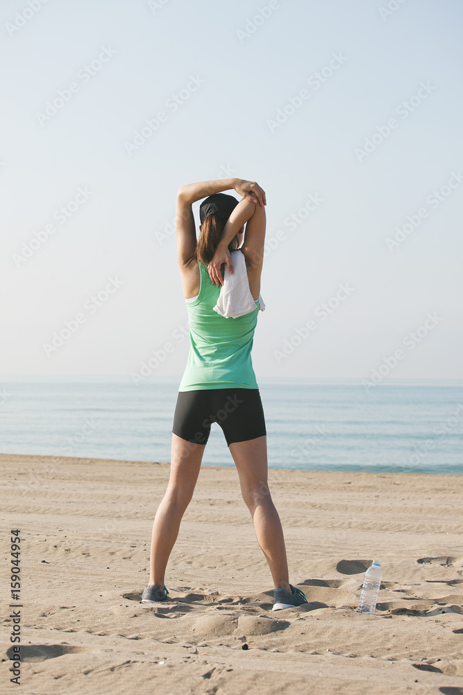 Sport girl doing stretching exercises after run workout on the beach Sport girl doing stretching exercises after run workout on the beach