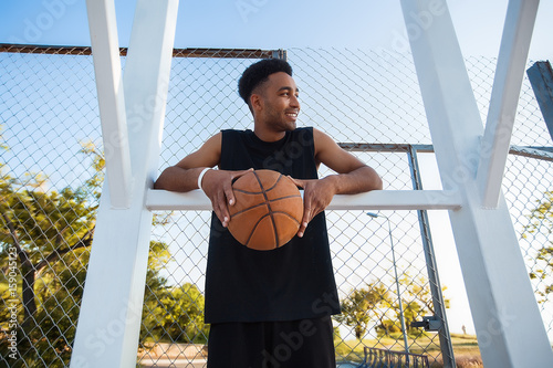 Man is holding a basket ball and laughing,street ball,sport competitions,afro,outdoor portrait,sport games,handsome black man,pretty,man holding ball,sportsman,black sport shorts,sports shoes