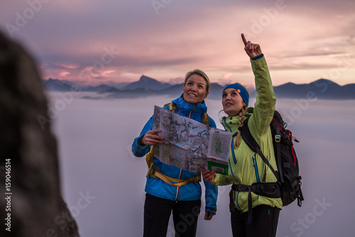two female hiker making a plan with a hiking map in alpine scenery