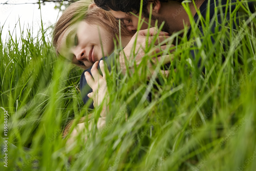 Young couple embracing in grass in nature in California Young couple embracing in grass in nature in California