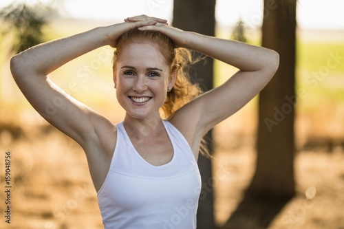 Smiling young woman exercising on sunny day at farm