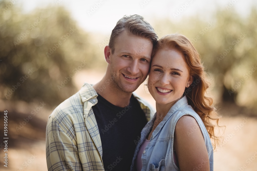 Portrait of happy young couple standing at olive farm Portrait of happy young couple standing at olive farm