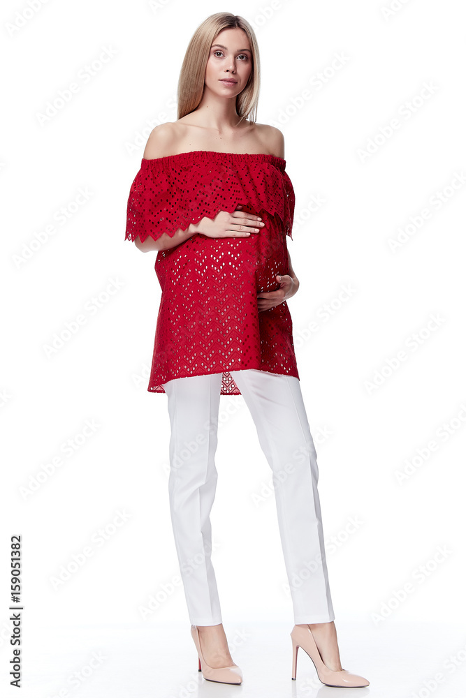 Beautiful elegant pregnant woman blond hair wear style fashion trousers red blouse for mother hold in hand tummy wait for baby child new born pretty clothes pregnancy white background casual heath. Beautiful elegant pregnant woman blond hair wear style fashion trousers red blouse for mother hold in hand tummy wait for baby child new born pretty clothes pregnancy white background casual heath.