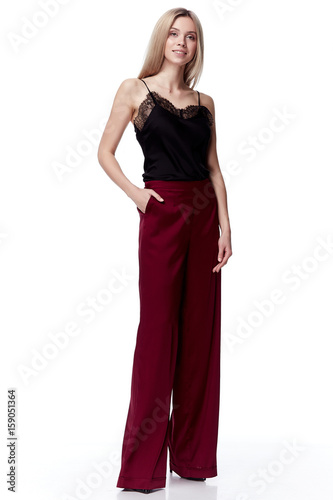 Beautiful sexy pretty fashion model blond hair woman wear bored red silk pants trousers and black blouse with lace style for party office clothes organic natural dress white background makeup lady. © indiraswork