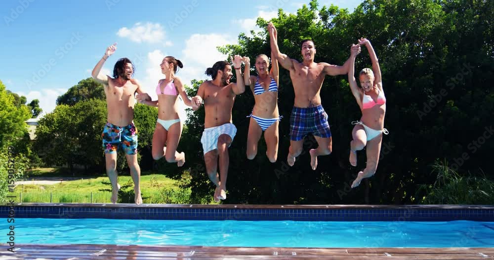 Happy friends jumping into swimming pool