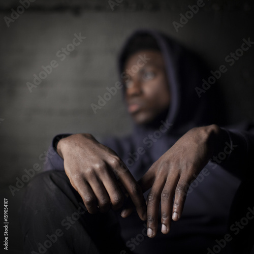 Sad black man in front of grunge wall