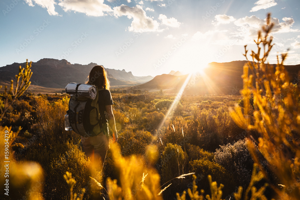 © Micky Wiswedel/Stocksy - Woman hiking with a backpack through a mountainous valley at sunset © Micky Wiswedel/Stocksy - Woman hiking with a backpack through a mountainous valley at sunset