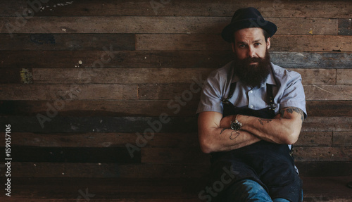 Portrait of stylish 30-something man with beard - sitting near reclaimed wood wall photo