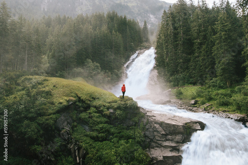 young woman standing in front of a beautiful waterfall