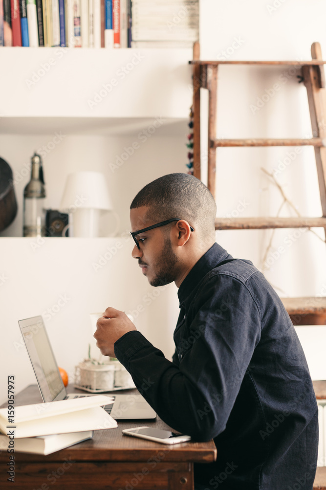 Side view of a latin man working with laptop at home office Side view of a latin man working with laptop at home office