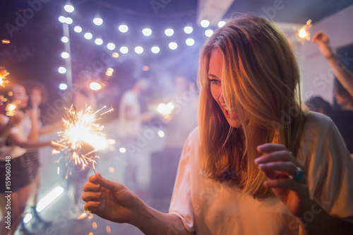 Woman holding sparklers at the party photo