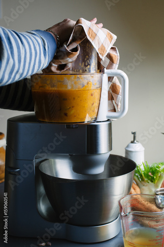 Woman's hands blitzing soup in the blender on a table photo