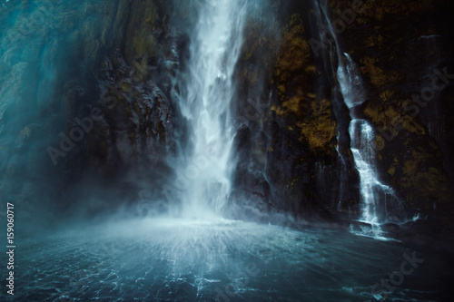 The rushing waterfall splashes into a cold New Zealand sound photo