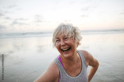 Vibrant mature woman enjoying herself on the beach at sunset