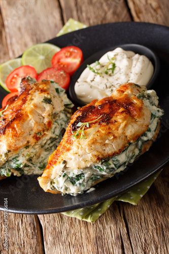 Baked chicken breasts with cheese and spinach filling with sauce close-up. vertical