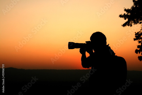 silhouette photographer taking photo of sunset light