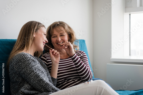 Teenage daughter with mother eating chocolate