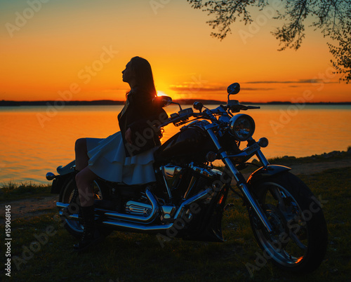 Young girl sitting on a motorcycle. Sunset.