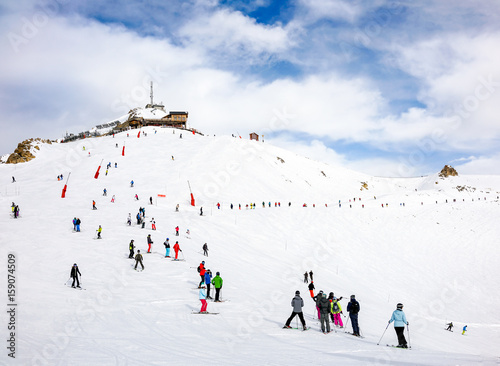 Skiers and snowboarders on the top station slope in Courchevel winter resort, France.