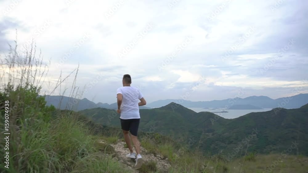 Jogging man on mountain road. Sport fitness boy stumble on mountain trail. Beautiful mountainous view Jogging man on mountain road. Sport fitness boy stumble on mountain trail. Beautiful mountainous view